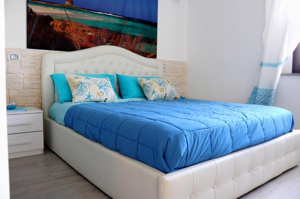 un letto bianco con lenzuola e cuscini blu di Appartamento La Pelosa a Stintino