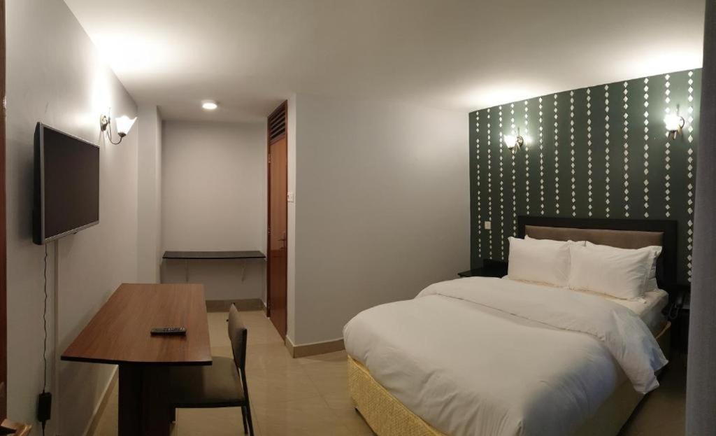 1 dormitorio con cama, mesa y escritorio en KABC Hotel, en Kigali