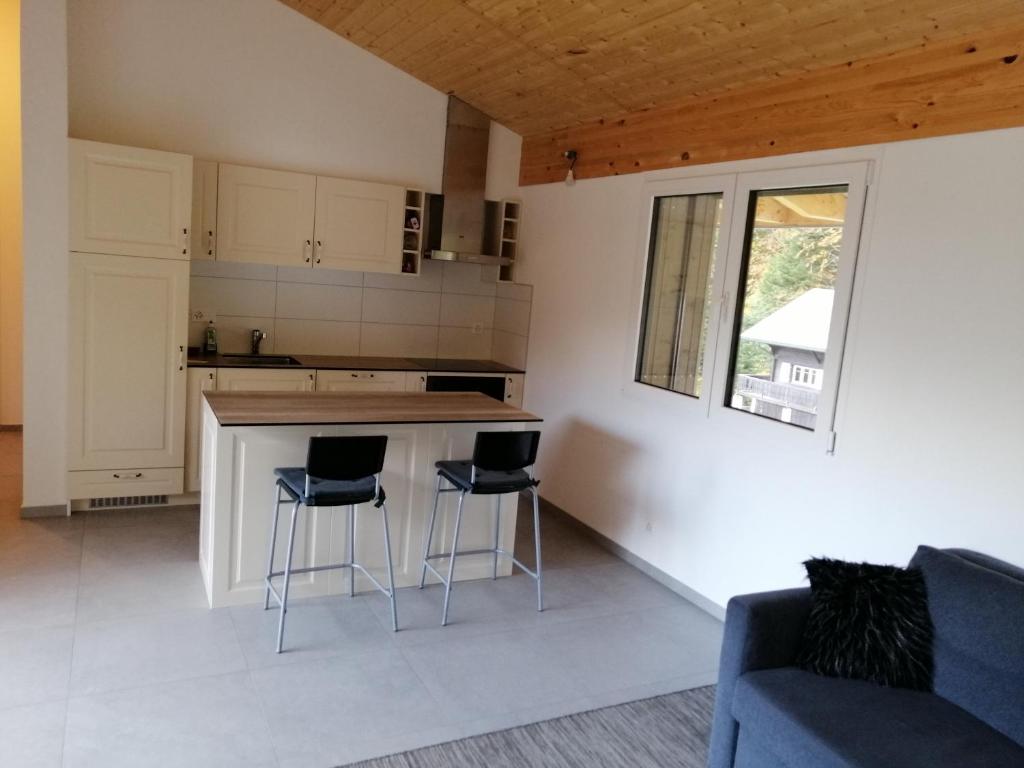 a kitchen with a counter and two bar stools at Le Petit Paradis du chalet Perce-Neige in Châtel-Saint-Denis