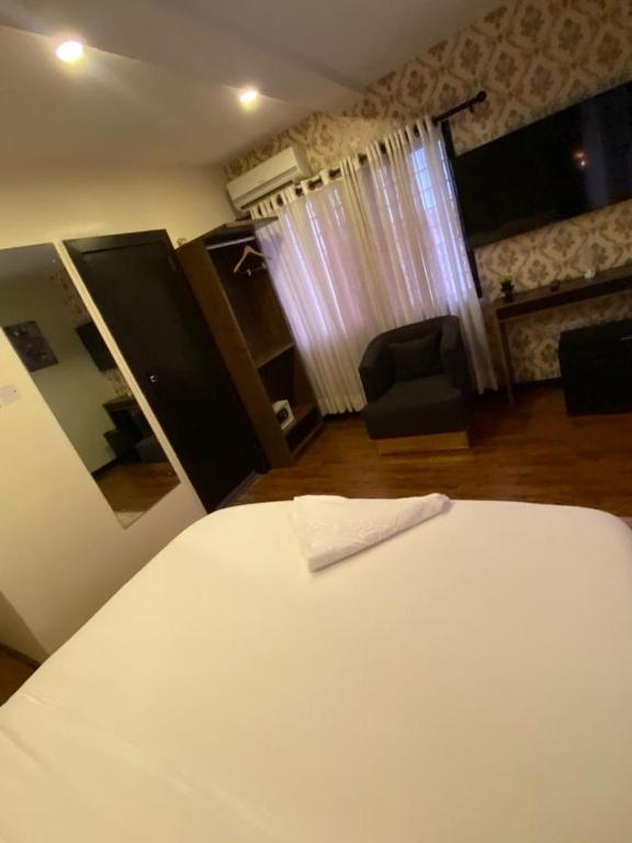 een slaapkamer met een wit bed en een kamer met een stoel bij KAFT2 HOTELS in Ijebu Ode