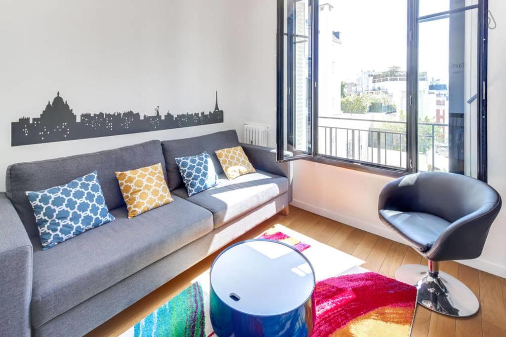 un salon avec un canapé et une chaise dans l'établissement Appartement Garros - Welkeys, à Boulogne-Billancourt