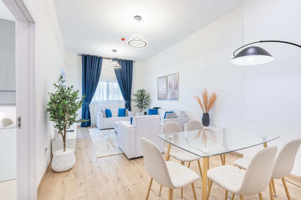 Luxurious Home in Silicon with Stylish Interior في دبي: غرفة معيشة بيضاء مع طاولة وكراسي زجاجية