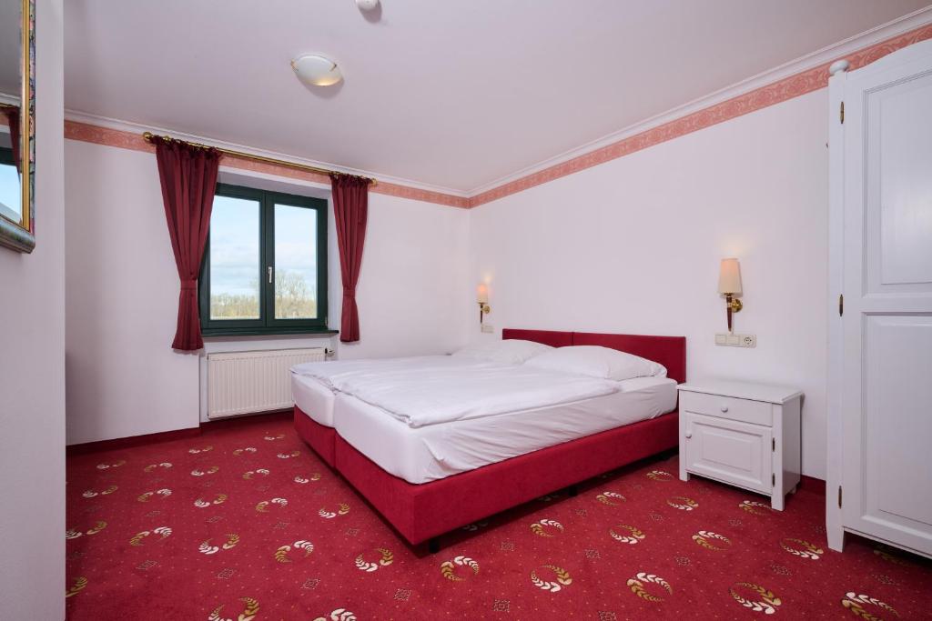 - une chambre avec un lit blanc et un tapis rouge dans l'établissement Tafernwirtschaft Hotel Schönbrunn, à Landshut