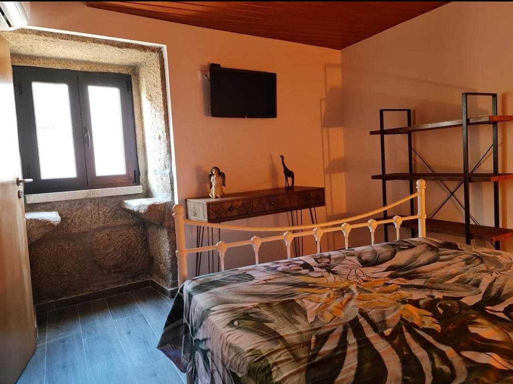 1 dormitorio con 1 cama y TV en la pared en Casa da Capela, en Entre Ambos os Rios