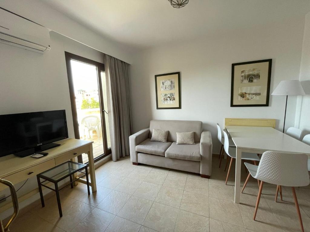 ein Wohnzimmer mit einer Couch und einem Tisch und einem Fernseher in der Unterkunft SEGUNDA PLANTA EN PRIMERA LINEA EN URB. JARDINES DE ISLA CANELA in Punta del moral