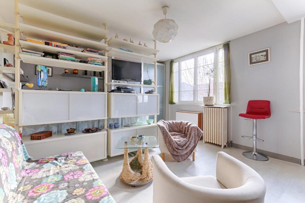 een woonkamer met witte meubels en een rode stoel bij Résidor - Cozy studio 10 minutes from Paris in Les Lilas