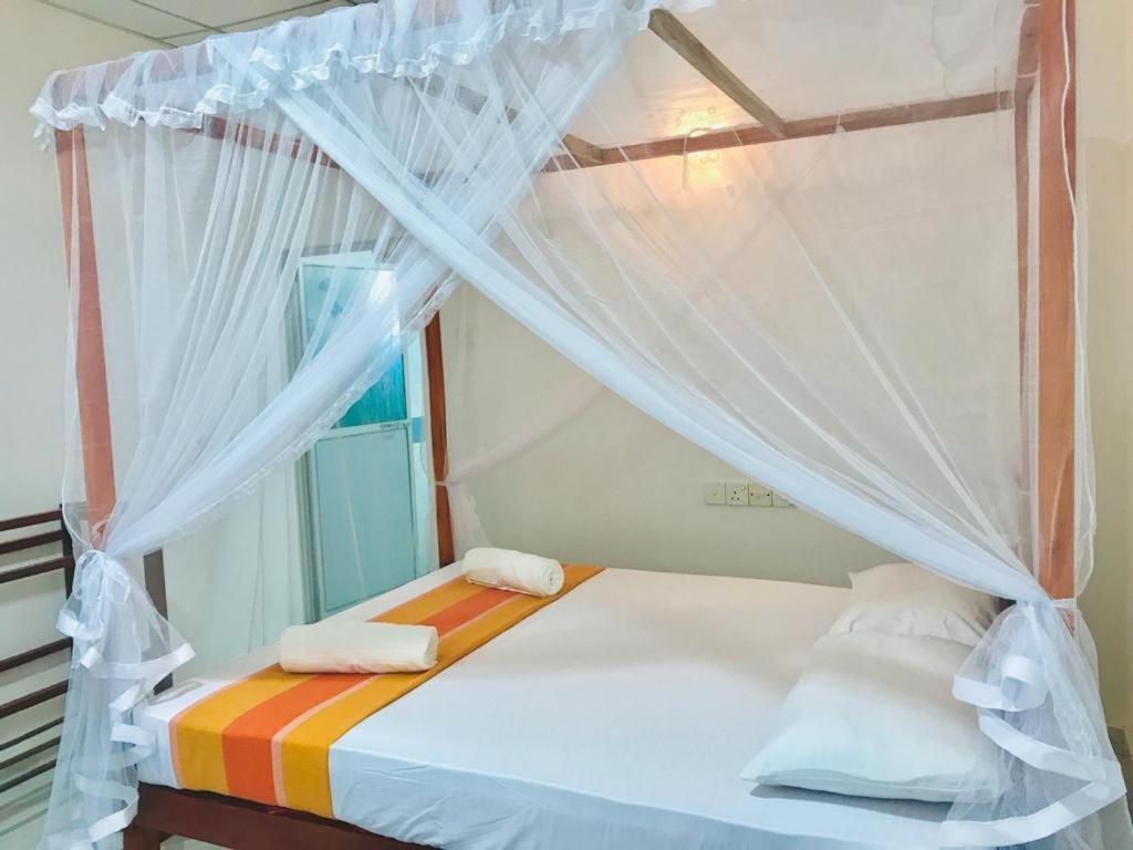 a bedroom with a canopy bed with towels on it at Tashil Hotel & Restaurant in Tissamaharama
