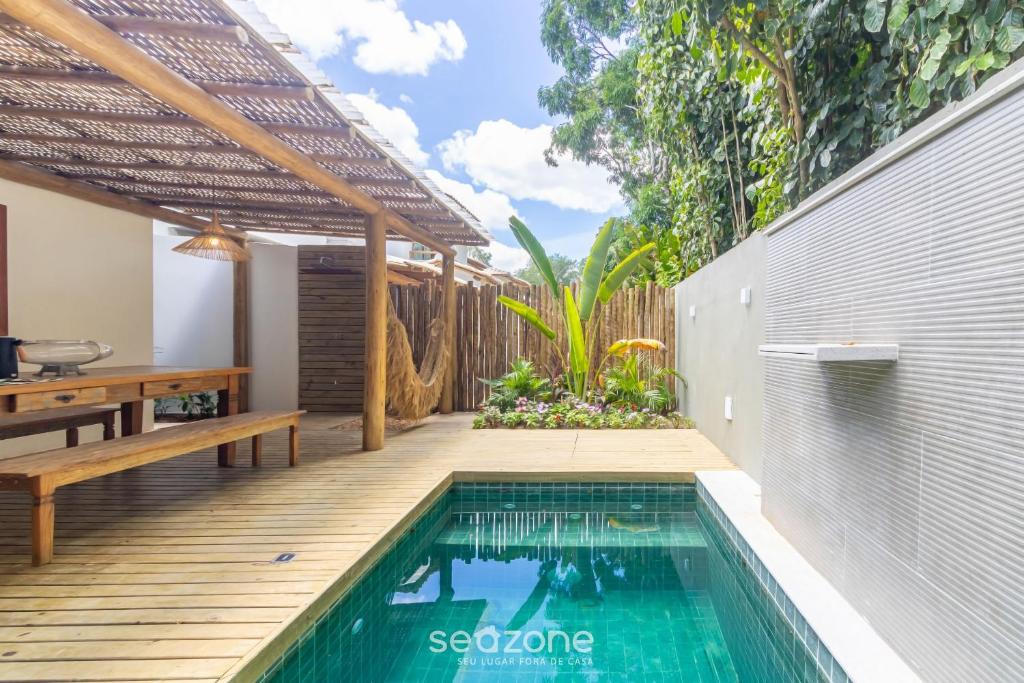 een zwembad in een achtertuin met een houten terras en een huis bij Casa c/ Piscina em Arraial D'Ajuda - CDO009 in Porto Seguro