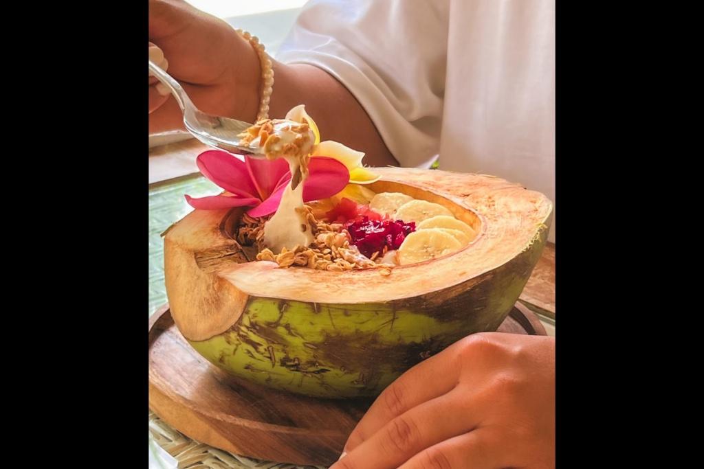 a person eating a bowl of food with a spoon at Rascals Hotel - Adults Only in Kuta Lombok