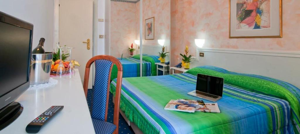 Zimmer mit 2 Betten und einem Laptop auf einem Tisch in der Unterkunft Hotel Sirius Riccione in Riccione