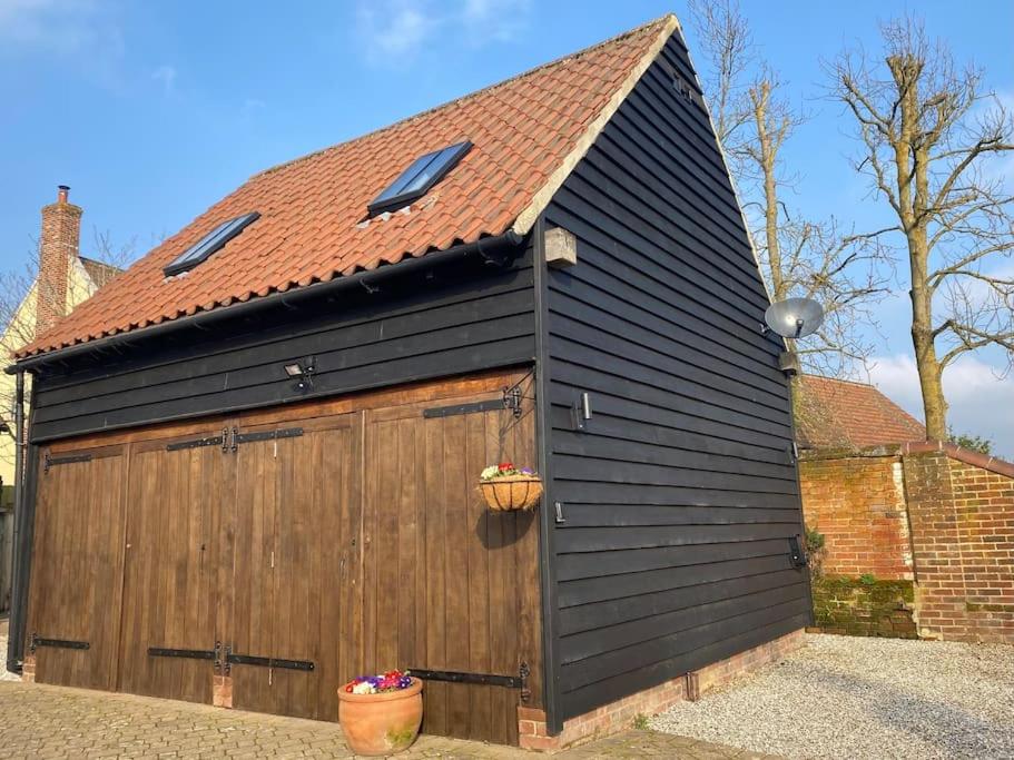 a black garage with a brown door and a red roof at The Cartlodge in Debenham