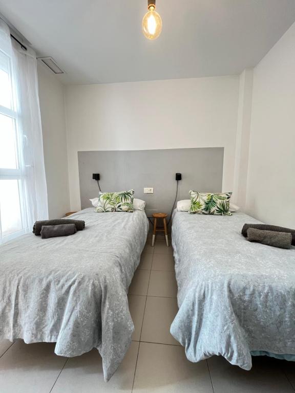 dwa łóżka w pokoju z białymi ścianami w obiekcie Apartamento San Juan 2 w Murcji