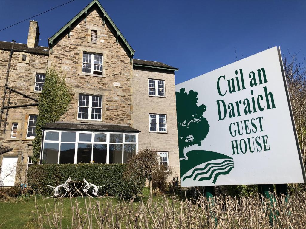 un edificio con un cartel frente a una casa en Cuil-An-Daraich Guest House, en Pitlochry
