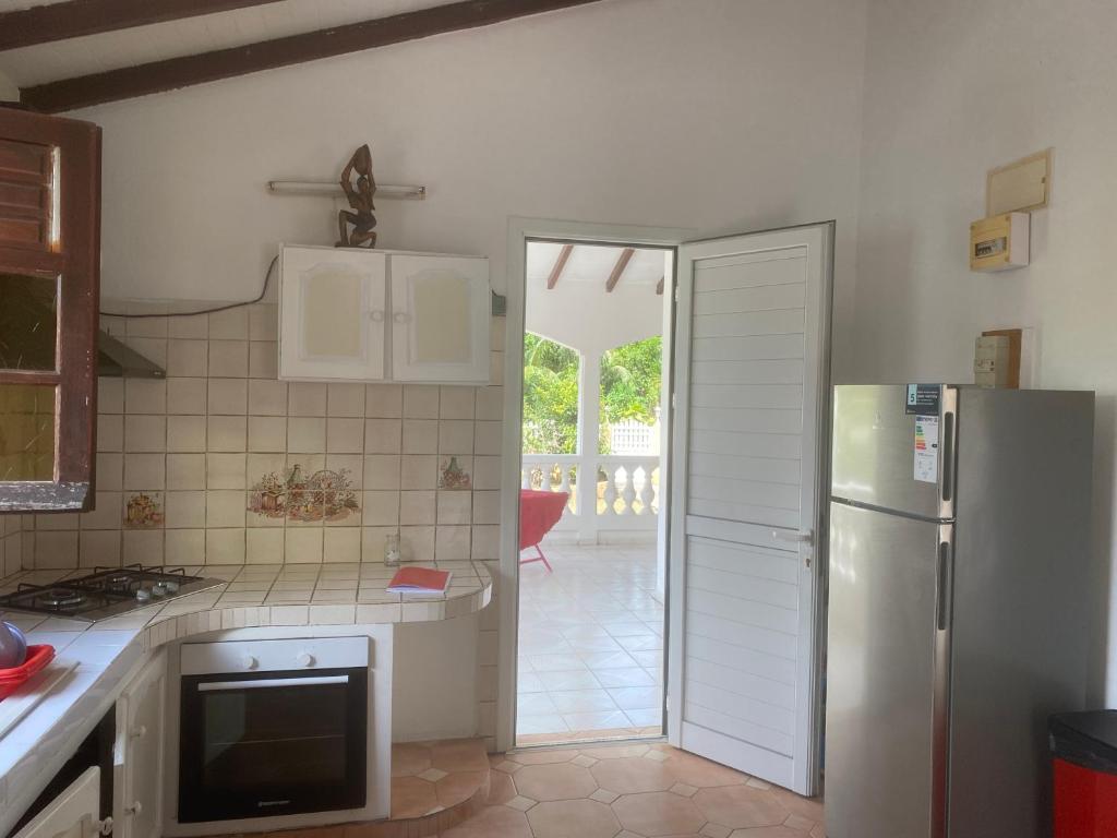 a kitchen with a refrigerator and a door leading to a patio at UN PLONGEON A la DEMEURE MOCENEA in Richemont