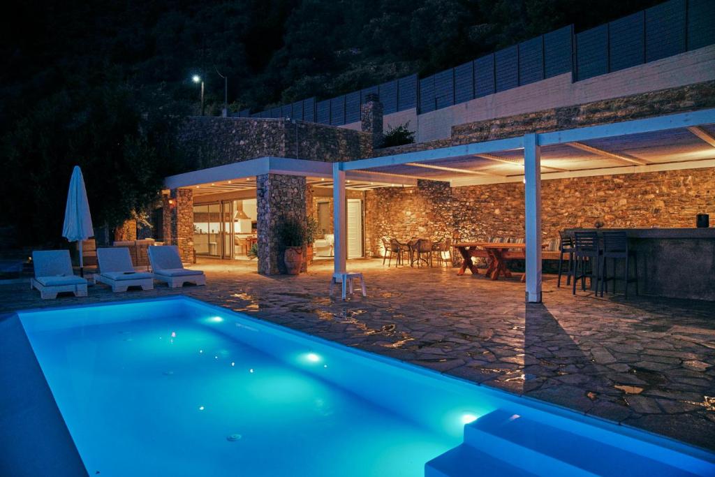 una piscina frente a una casa por la noche en La Bella Villa, en Melínta