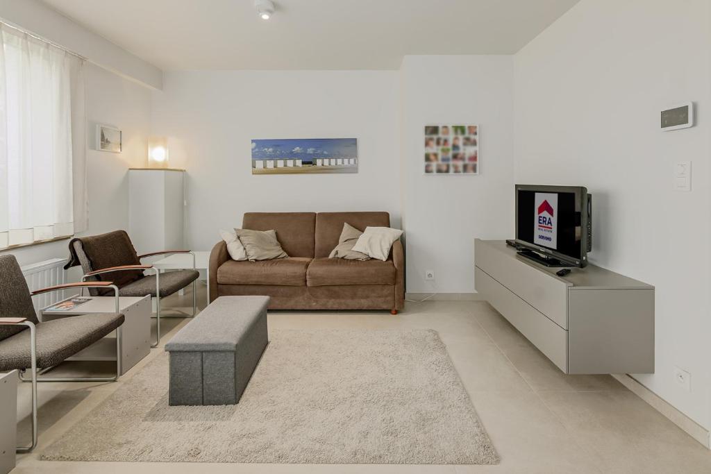 een woonkamer met een bank en een tv bij Les Lucioles Gv01 in Oostduinkerke