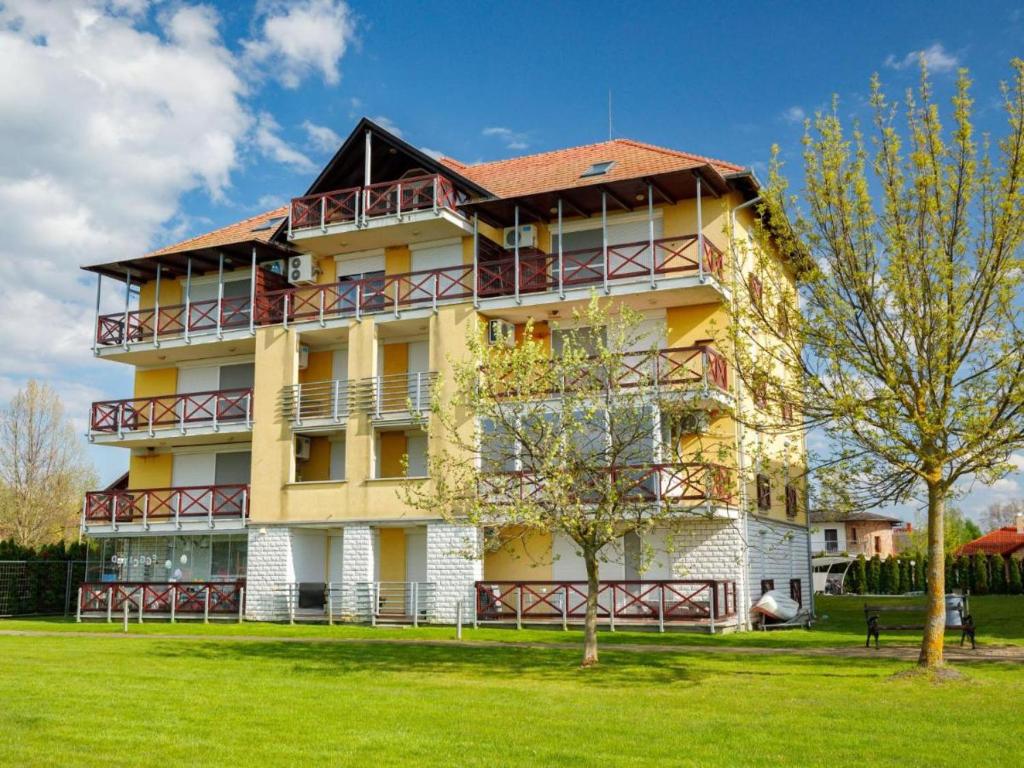 een groot geel gebouw met een rood dak bij Like Home Apartman Balatonőszöd in Balatonőszöd