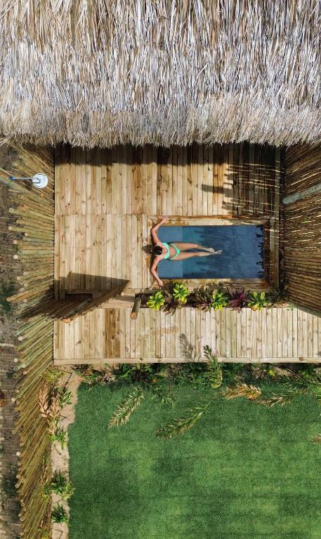 ein strohgedecktes Haus mit Swimmingpool in der Unterkunft Vila Flor Studios in Praia de Moitas