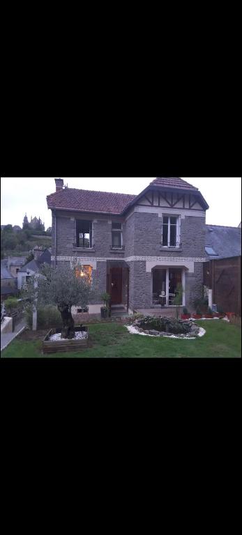 une grande maison en briques avec un arbre dans la cour dans l'établissement Maison papillon, à Fougères