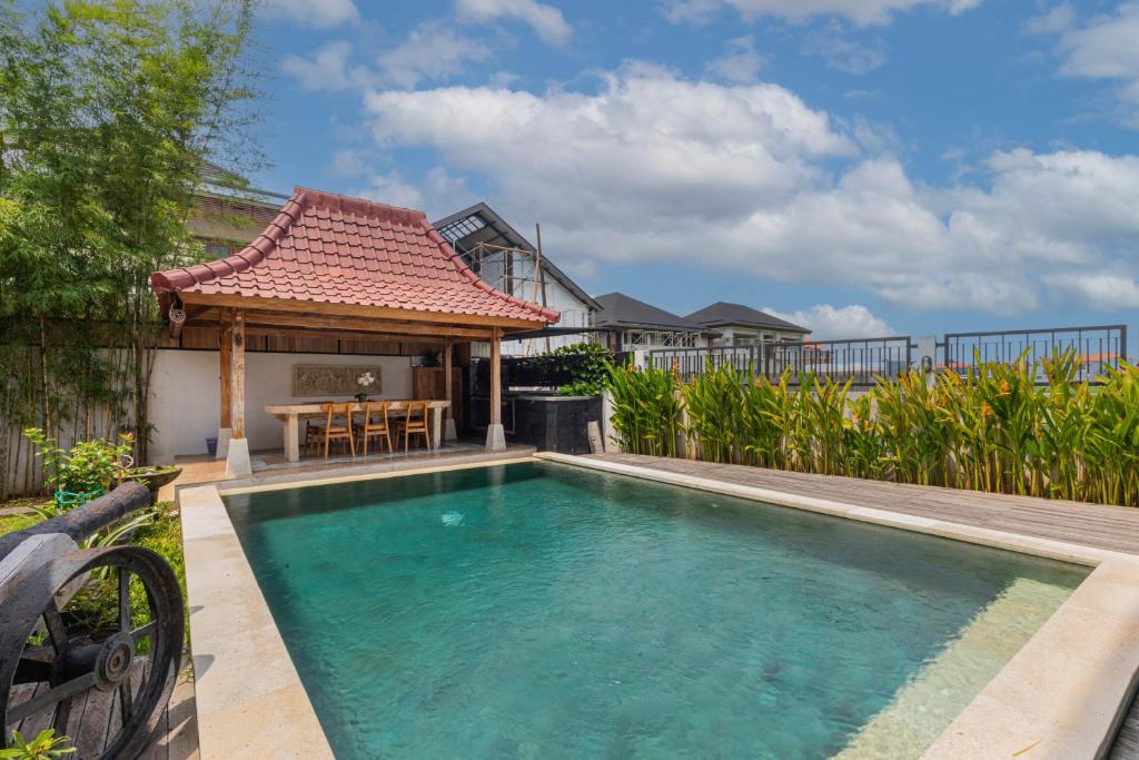 a swimming pool in front of a house with a gazebo at Casa Yumi in Denpasar