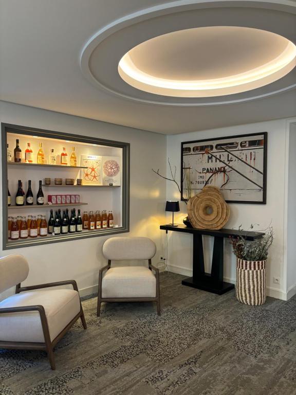 a room with a bar with two chairs and a table at Hôtel De La Marine in Arromanches-les-Bains