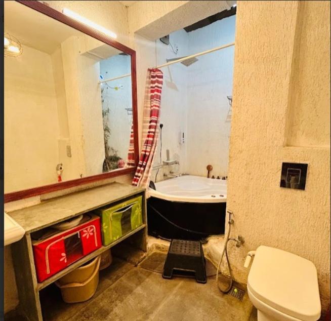 ein Badezimmer mit einer Badewanne, einem Waschbecken und einem WC in der Unterkunft Garnet Crove Villa in Alībāg