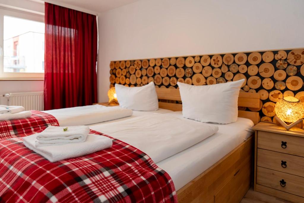 2 aparte bedden in een kamer met een rood gordijn bij Rosewood - Apartment by Comfort Housing in Falkensee