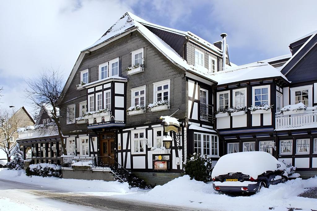 ein schneebedecktes Haus mit einem davor geparkten Auto in der Unterkunft Landhotel Albers in Schmallenberg