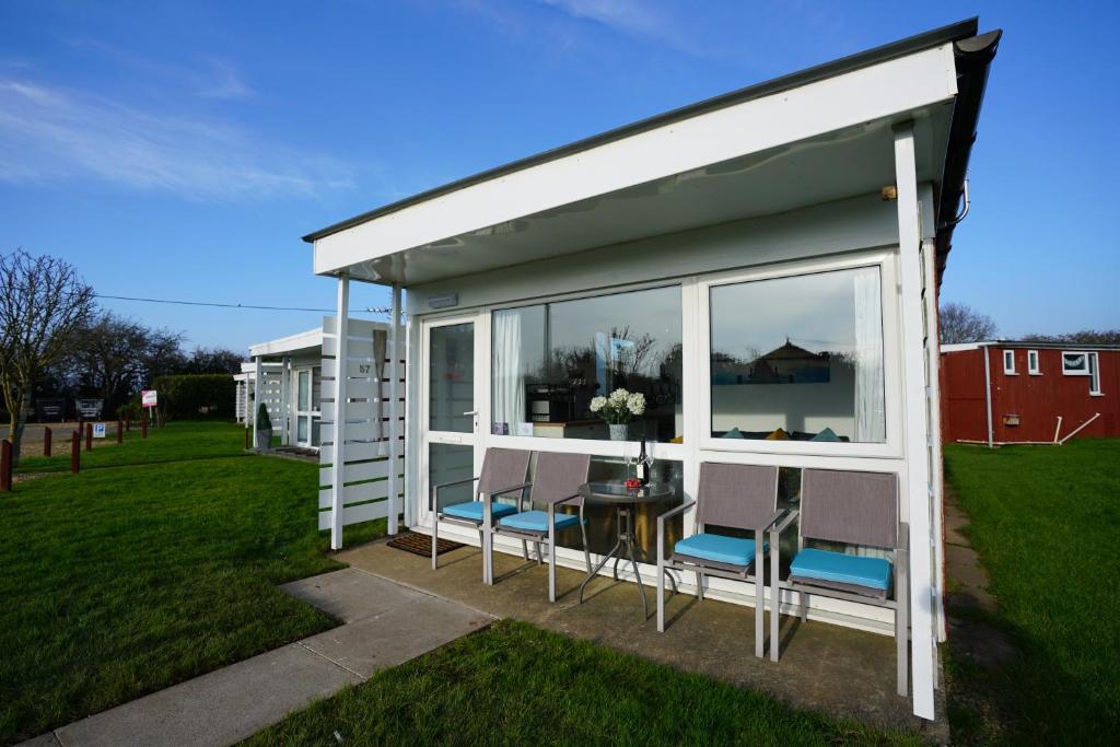 a house with chairs and a table in a yard at Sea Lavender Holiday Chalet, close to sandy beach in Heacham