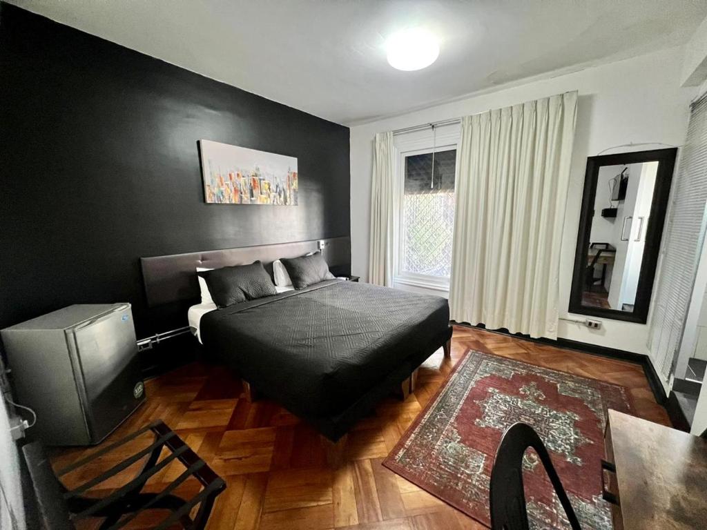 a black bedroom with a bed and a television at Hotel Bellavista Santiago Suite in Santiago