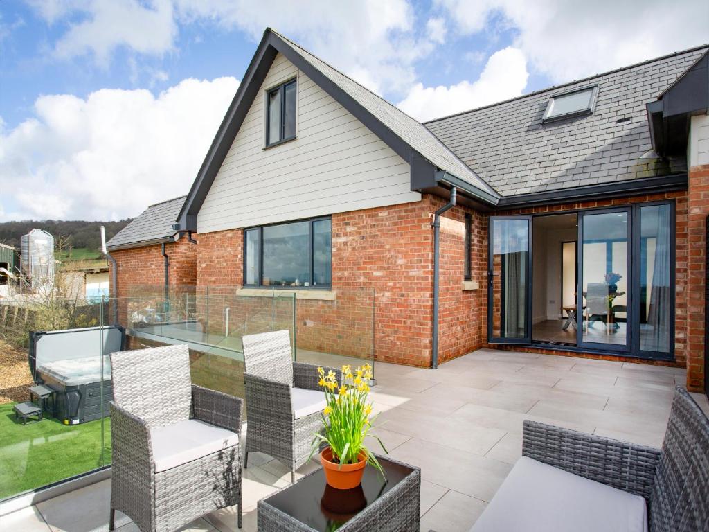 a brick house with a patio with chairs at Deer View in Ottery Saint Mary