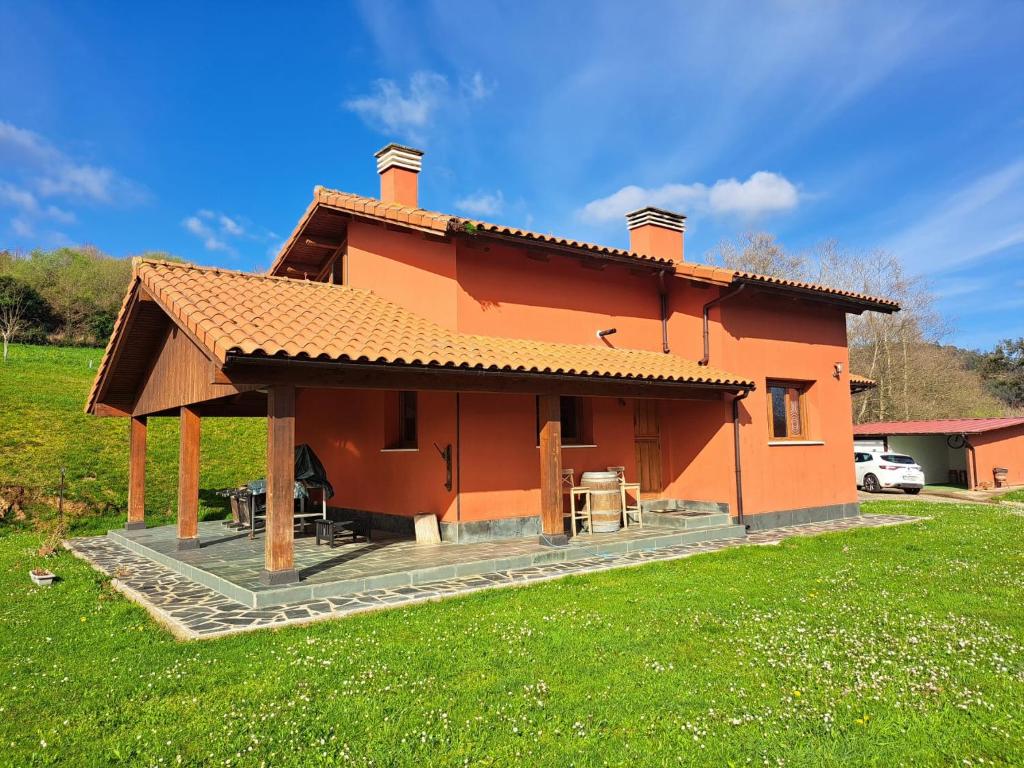 a small orange house in a field of grass at La Casita de Tití in Pravia