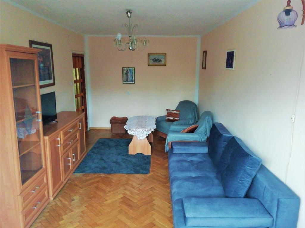 a living room with a blue couch and a table at Apartament Szczytno centrum in Szczytno