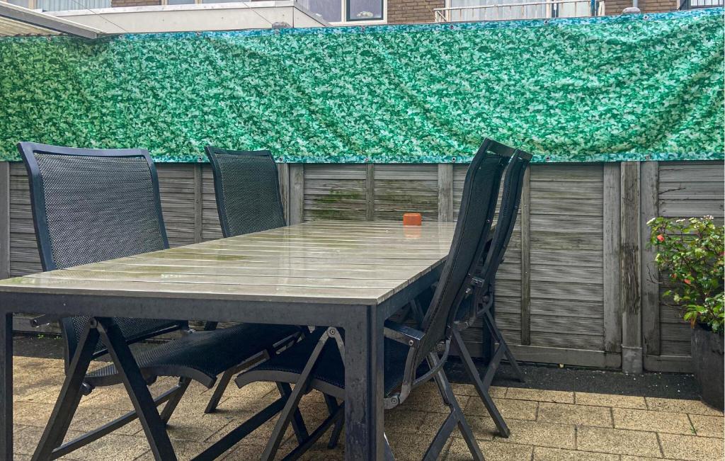 a table with four chairs and a green wall at Pet Friendly Home In Egmond Aan Zee in Egmond aan Zee