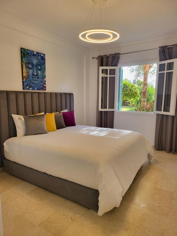 a bedroom with a large white bed with a window at Appartement Oxygène Marrakech Sun in Marrakesh