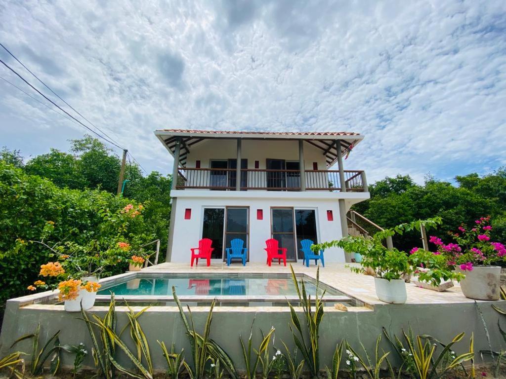 托盧的住宿－Cabaña cerca al Mar con Pisicina y AC en Tolú，一座带游泳池和红色椅子的房子
