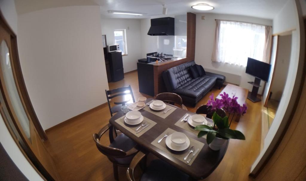 a living room with a table and chairs and a couch at Guest House Nishimiyanosawa in Teine