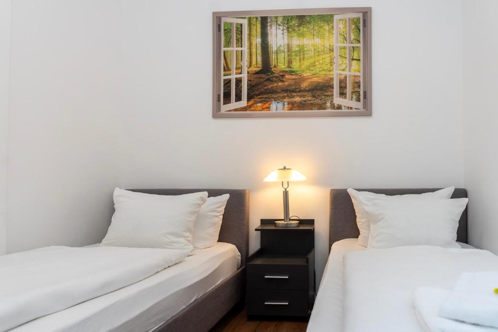 two beds in a room with a picture on the wall at Cosy Nest - Apartment by Comfort Housing in Falkensee