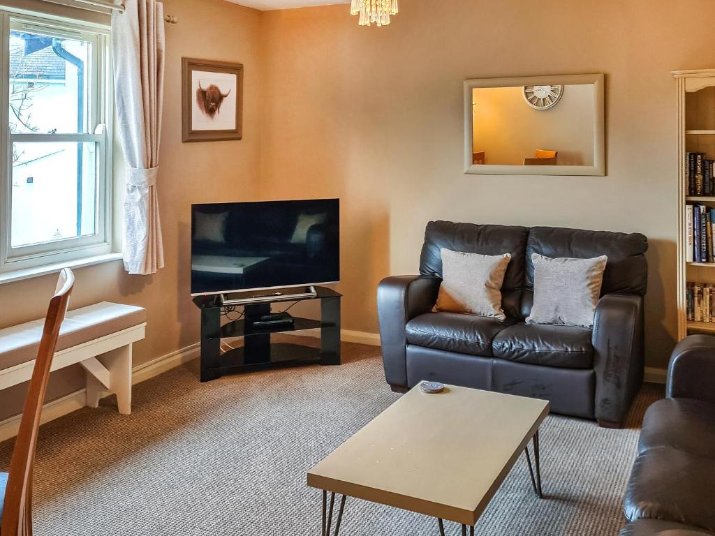 a living room with a leather couch and a tv at 10 Elm Court in Keswick