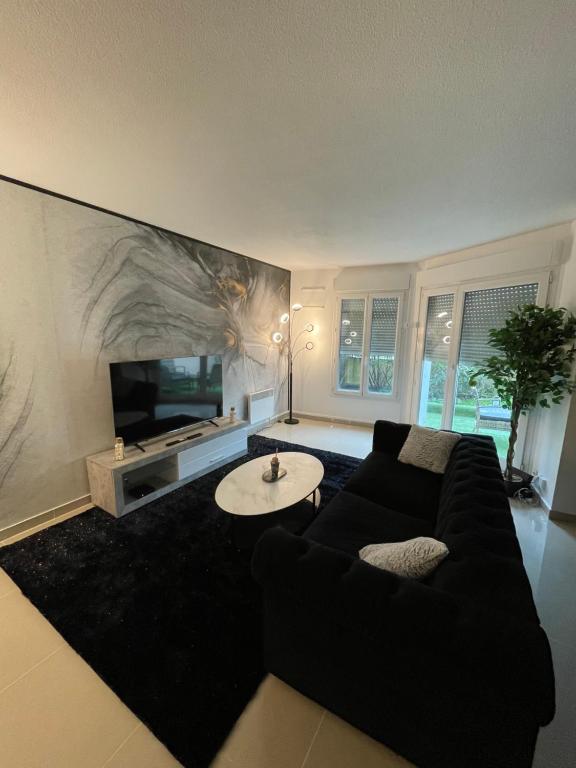 a living room with a black couch and a tv at BY NEPTUNE - Appartement Disney Paris - 1 min RER in Chessy