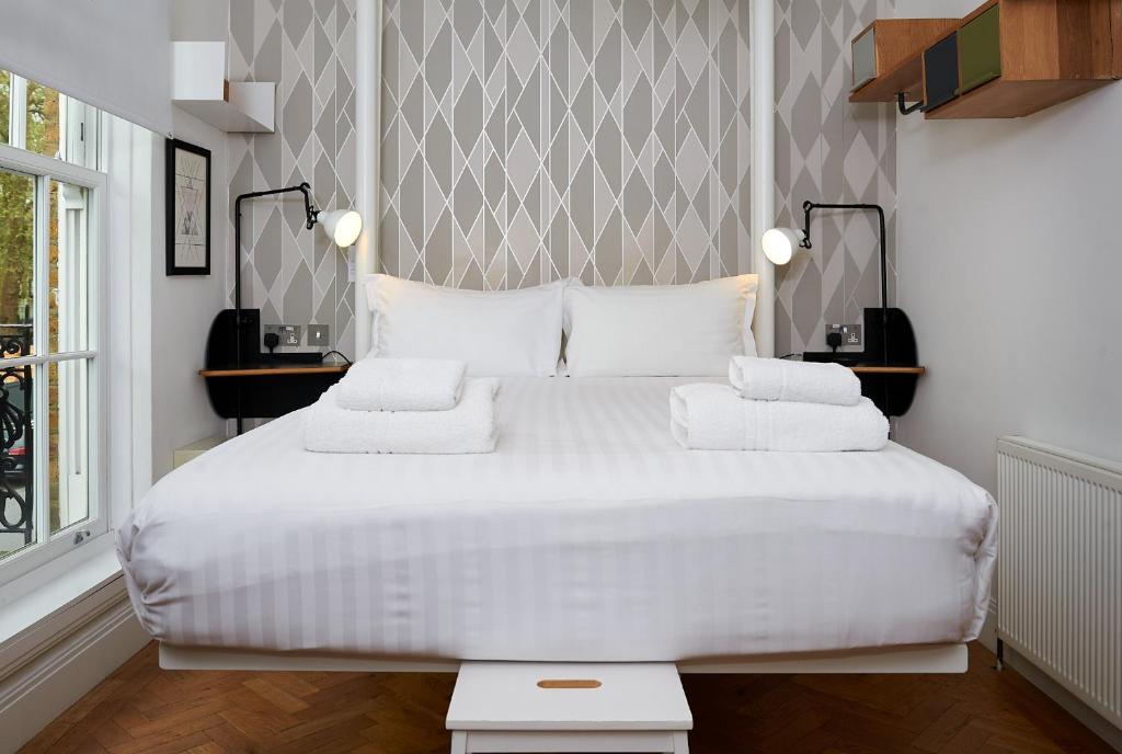 a bedroom with a large white bed with white pillows at The California - London Kings Cross in London