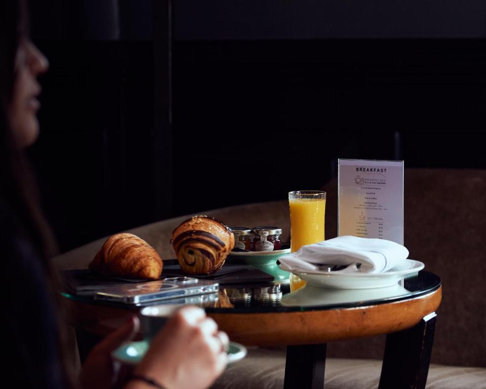 a table with a plate of bread and a glass of orange juice at The California - London Kings Cross in London