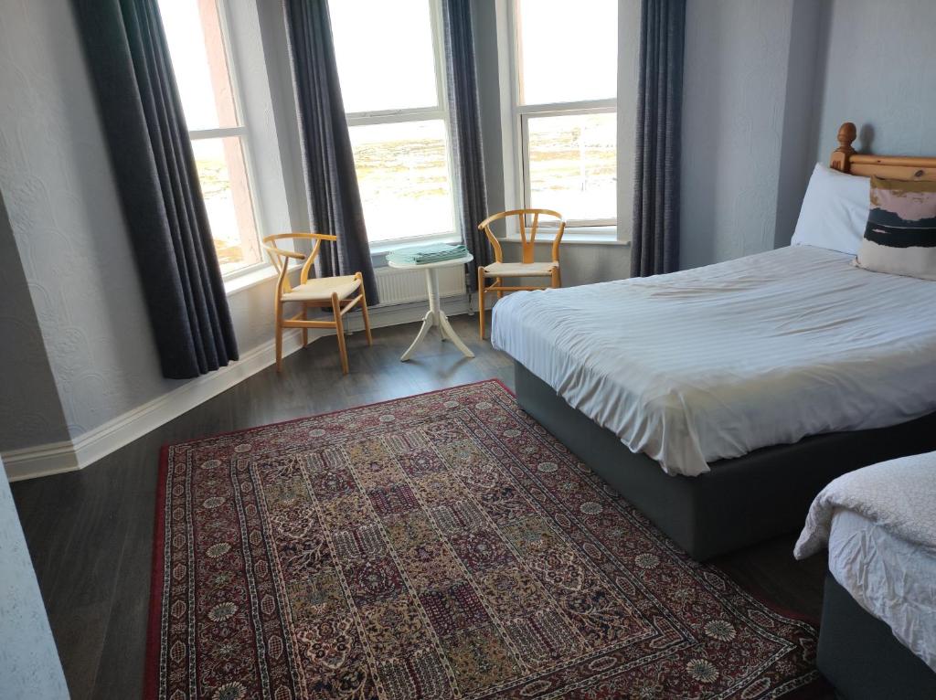 a bedroom with a bed and two chairs and a rug at 4 Bayview terrace in Bundoran
