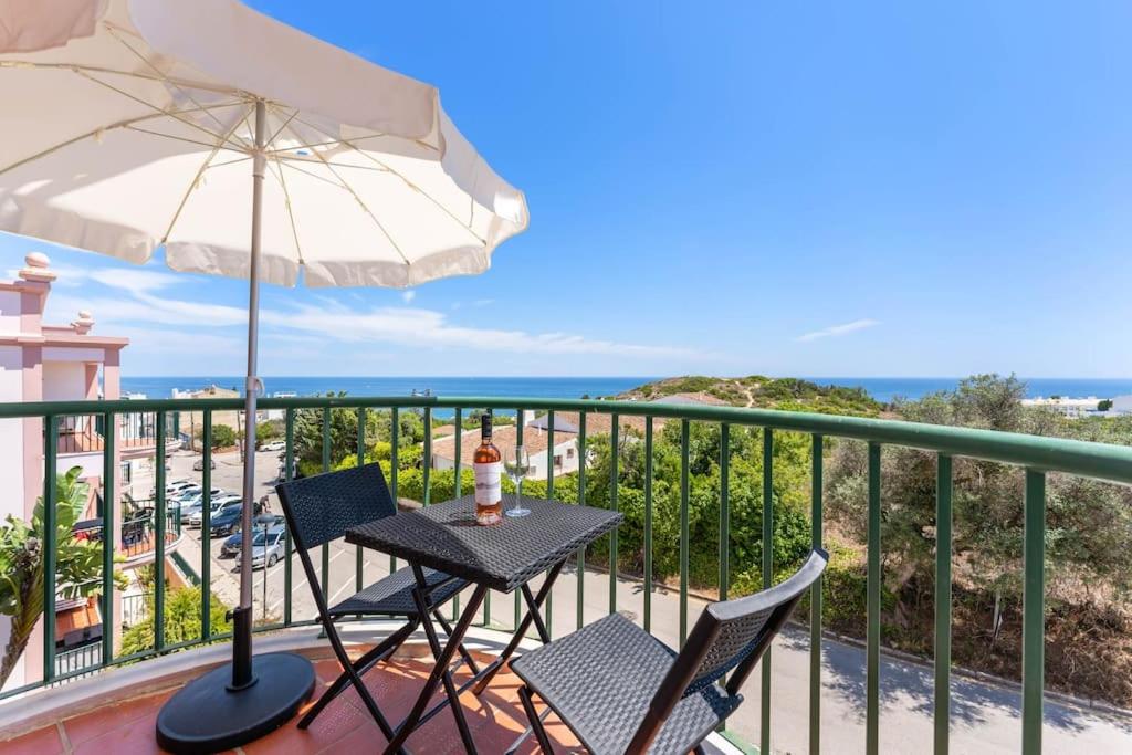 a table and chairs on a balcony with an umbrella at Paz e Vista Mar with Pool & WiFi in Luz