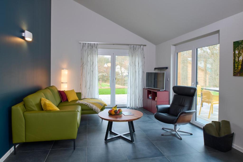 sala de estar con sofá verde y mesa en Traumweiler Ferienhäuser am Waldrand en Kirschweiler