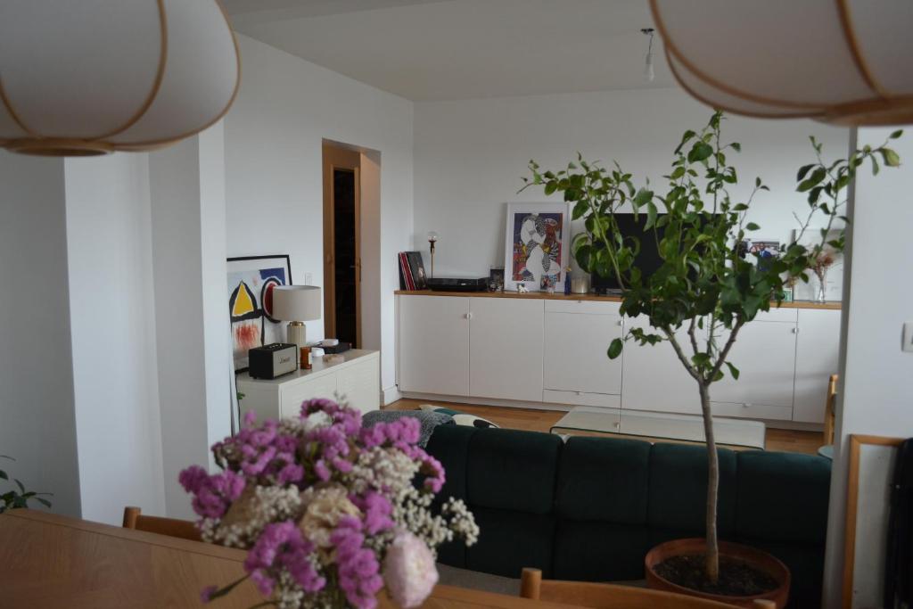 - un salon avec un canapé vert et des fleurs violettes dans l'établissement Charmant T4 proche Paris (métro), à Ivry-sur-Seine