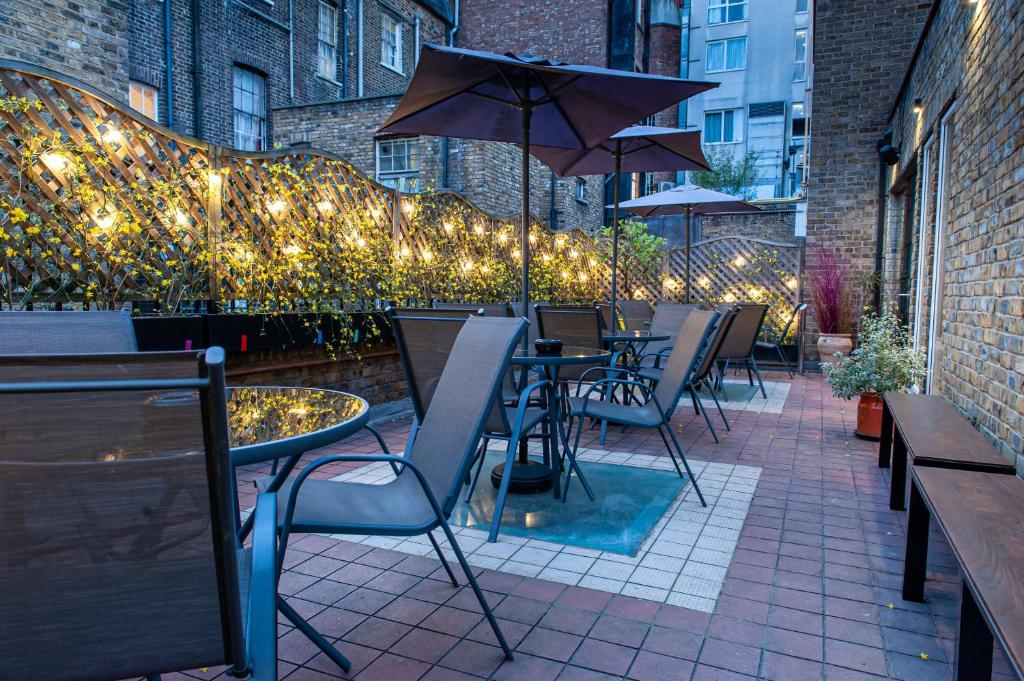 a patio with tables and chairs and an umbrella at The California - London Kings Cross in London