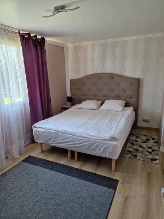 - une chambre avec un lit et un rideau pourpre dans l'établissement Maisonnette, à Auneuil