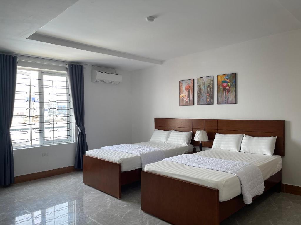 a hotel room with two beds and a window at IVY Homestay in Hai Phong