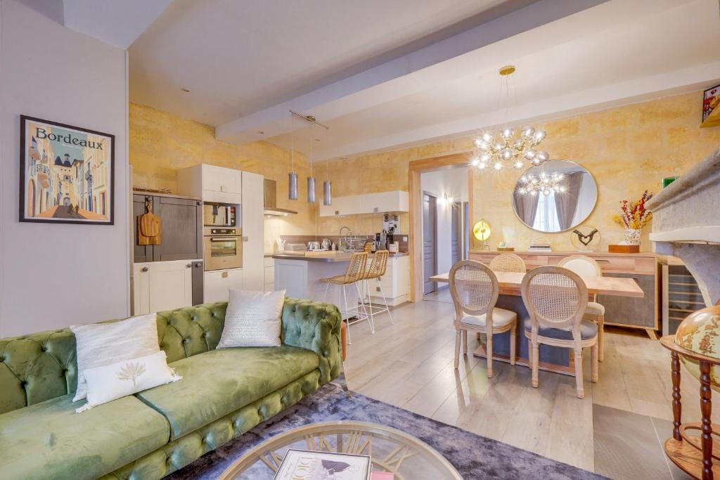 un salon avec un canapé vert et une cuisine dans l'établissement Le Précieux - Appt Place de la Victoire, à Bordeaux